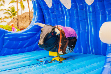 Close up view of mechanical bull attraction on blue inflatable mat at tropical resort area. Dominican Republic. Punta Cana. 