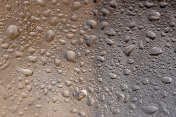 a whole wet old glass lies on a black board with an uneven texture, a whole sheet of transparent glass used in construction covered with water droplets