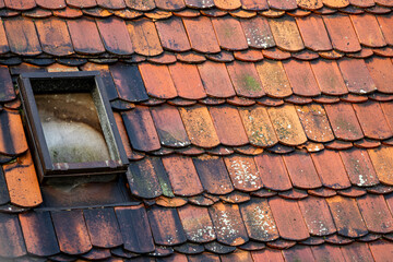 Old red clay roof tiles with weathered skylight window
