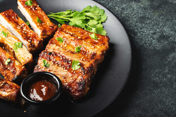 Hot grilled spare ribs from a summer BBQ served on a plate with sauce. Top view. Copy space