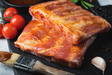Ready for BBQ raw pork spare ribs with barbecue sauce. Black background. Top view