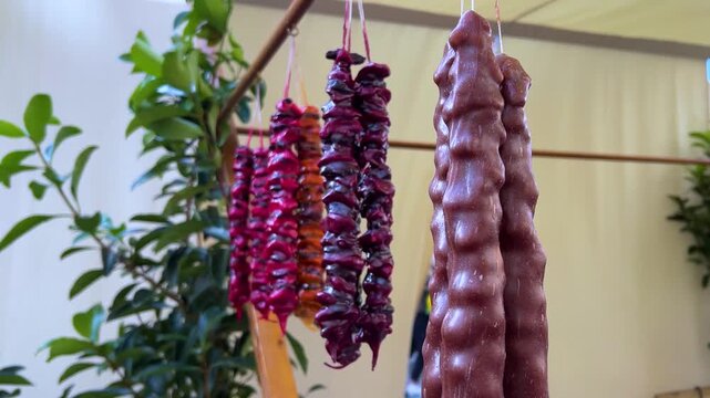 Horizontal 4K video. 60 fps. Georgian dish red, brown churchkhela hanging on rope on Christmas festival, city holiday Tbilisoba, New Year market, autumn harvest fair, pastry shop. cuisine, sweet food
