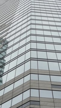 Corner perspective of a modern glass skyscraper facade with reflective grid windows, clean lines, and geometric repetition, highlighting sleek urban architecture