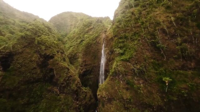 FPV Drone View of a Thin Wterfall Cascading Down a Lsh Green Mountain