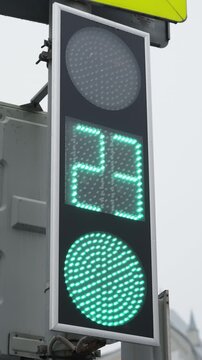 Pedestrian traffic signal with green LED countdown timer, showing decreasing seconds on a numeric display and illuminated circular light at an urban crosswalk, highlighting safety