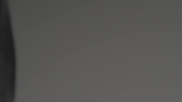 Close-up view of professional hairdresser hands with black nails carefully trimming damaged split ends of red hair using comb and sharp scissors in beauty salon.

