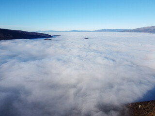 Fog and clouds covering the valley, drone footage. Air pollution trapped under cloud inversion. Flight above the clouds. 