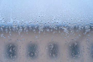 window glass covered with raindrops, window with a view of the building