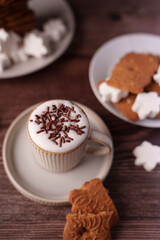 cozy winter indulgence: cappuccino with chocolate sprinkles and festive biscuits on wooden table creating warm and inviting ambiance for relaxation and enjoyment, bliss, delight, afternoon