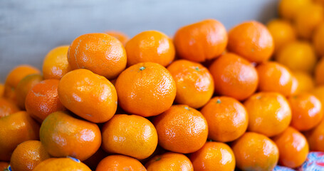Ripe, freshly picked tangerines in a box at a farmer market. Abundant supermarket window with citrus fruits close up