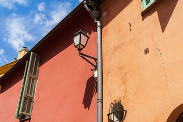 Vibrant terracotta and red stucco walls of an old Mediterranean building featuring a vintage black...