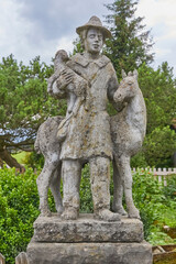 Fototapeta premium Schöner rustikaler Brunnen mit einer Figur bei einem Bauernhaus in der Nähe der Ortschaft “Seeg im Allgäu“, Deutschland, Bayern.
