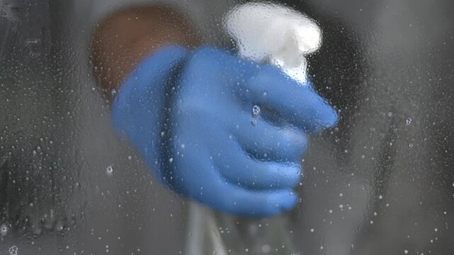 Cleaning a window using a spray bottle and cloth in a well-lit space