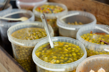 Plastic buckets are filled with pickled olives in brine. Wide range of vegetable store, fresh and processed vegetables and fruits.