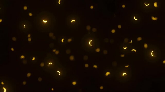 Golden crescent moon shaped bokeh lights floating on dark background resembling solar eclipse shadows
