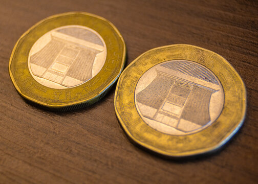 The image features Ghanaian 2 Cedi coins, which are distinctive bimetallic pieces with a ten-sided shape. The reverse displays the Jubilee House (Presidential Palace).