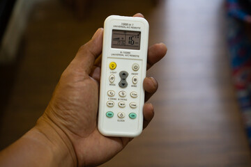 Close Up Of A Hand Holding A White Air Conditioner Remote Control With Digital Display And Buttons