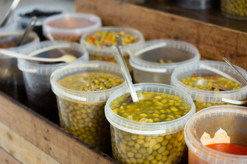 Marinated olives in plastic containers on a shelf in a supermarket