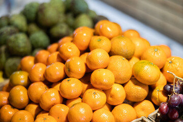 Ripe, freshly picked tangerines in a box at a farmer market. Abundant supermarket window with citrus fruits close up