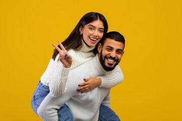 Two people enjoy a playful moment together, with one person giving a piggyback ride while smiling...