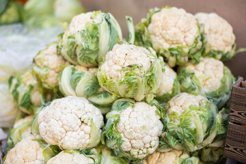 Fresh cauliflower harvest in a wicker box on a supermarket counter. Farm vegetables at the market close up