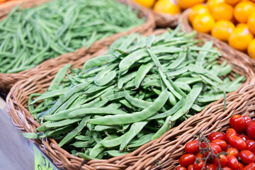 Fresh green string bean in a box on the counter of a stall. Vegetables and beans are on a shelf in a supermarket