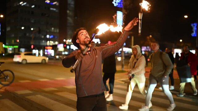 Street artist juggling flaming torches at night in the city