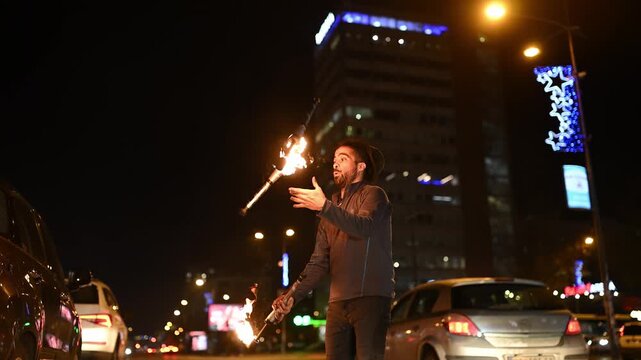 Street performer juggling flaming torches at night in the city
