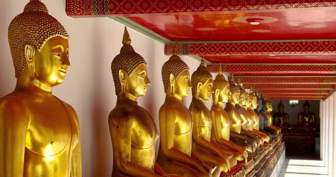 Row of Golden buddha statues inside historic wat pho temple interior a famous conic Bangkok buddhist landmark, Thailand.