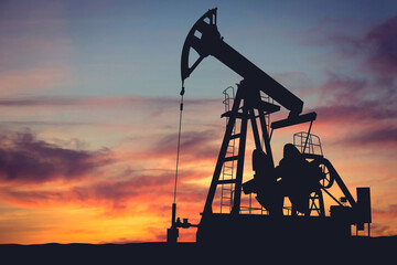 Silhouette of oil pumps against a sunset. Illustration of the oil production process in an oil field. Symbol of energy, industry, and the global economy.
