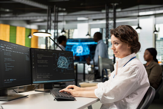 Computer scientist in artificial intelligence tech company workplace conducts code reviews. Woman using PC application at office desk to design and implement machine learning algorithms