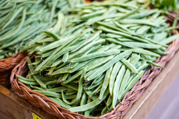 Fresh green string bean in a box on the counter of a stall. Vegetables and beans are on a shelf in a supermarket