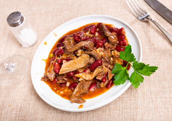 Stewed beans with mushrooms, herbs and spices on a plate view from above. Traditional Spanish dish with beans and sauce
