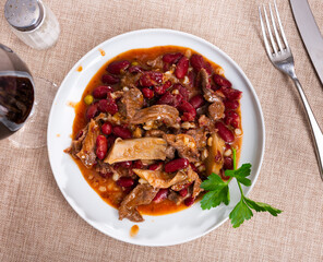 Stewed beans with mushrooms, herbs and spices on a plate view from above. Traditional Spanish dish with beans and sauce