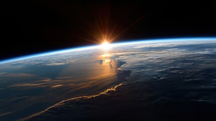Light from the sun rises over the horizon of Earth illuminating clouds and ocean. The scene shows the curvature of the planet in the vastness of space.