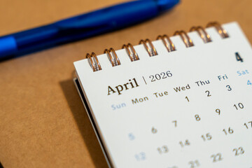 A close-up of a spiral-bound calendar page showing April 2026. Accompanying a blue pen, it signifies planning and organization for future appointments or events. © daily_creativity