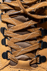 A close-up of a brown hiking boot lace-up system showcasing intricate lacing details, designed for outdoor activities and adventures in nature, emphasizing durability and functionality.