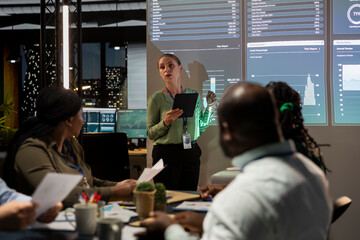 Female consultant presenting project details and timetables in conference room, establishing budget and operations plan to accomplish objectives in a competitive business environment.