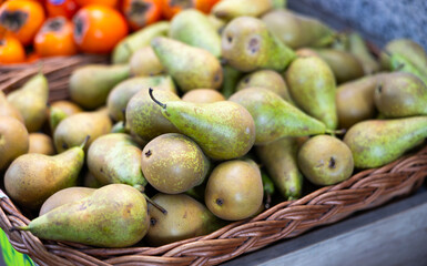 View of ripe pears in a wicker basket, put up for sale in a store