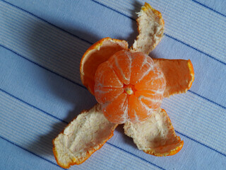 Whole ripe peeled orange clementine on blue cloth