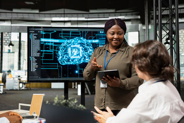 IT professionals doing meeting in company conference room, implementing AI solutions to increase productivity. Multiethnic technicians discussing machine learning models roadmap in startup office