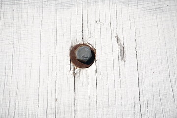 A top-down macro shot of a single hexagonal metal bolt and a rusted washer embedded in a...