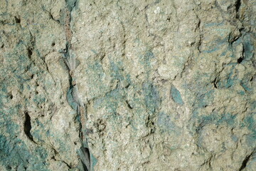 an uneven stone surface characterized by a unique pale green and teal patina. The texture is porous and crumbly. © 1975boomerang
