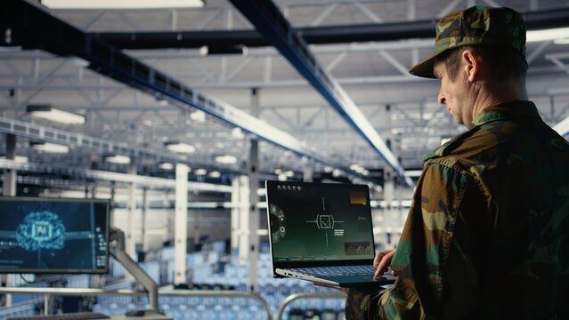 Military data center specialist using radar software on laptop to watch for enemy threats. Army soldier in data center scans suspicious activity to detect dangers using notebook, camera A