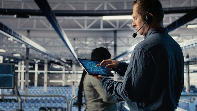 Data center engineer using AI on tablet to help clients resolve website hosting problems. Server hub tech support specialist helping users keep their online services running smoothly, camera A - Powered by Adobe