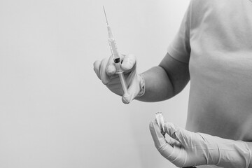 Medical professional holding a syringe and an ampoule on a white background.