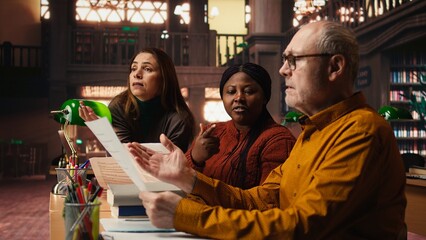 Diverse actors team reading their scripts during theatre drama play rehearsal in library, showing dedication to script practice. Role preparation together for dramatic arts reenactment.