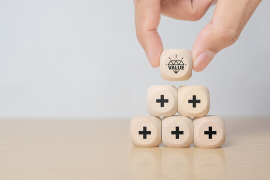 Value added concept. Way to adding value to product and service. Hand choose wooden blocks with value added icons. Improving products, excellent service, expert advice, consistently upgrade