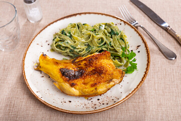 Delicious chicken thigh and spinach pasta closeup