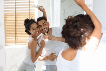 A happy couple brushes their teeth together in a bright bathroom. They share smiles and laughter...